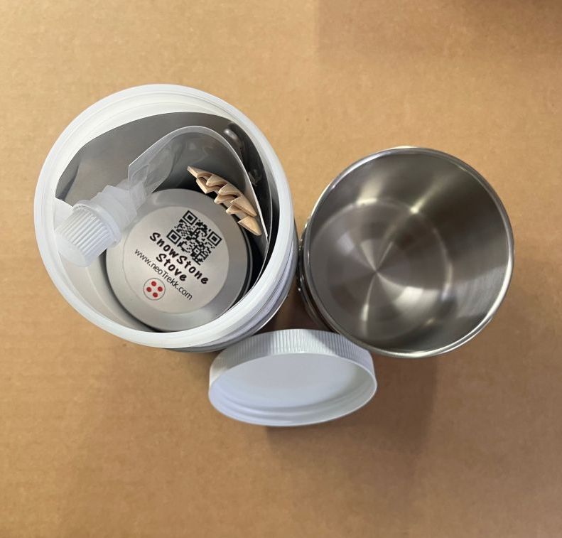The Koozy Kitchen Kit from above: the insulated jar with the SnowStoneStove inside, next to a steel mug